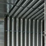 Hammer drive anchors securing HVAC ventilation ducts and metal piping to ceiling structure
