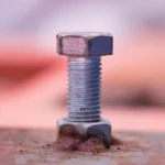 Steel hex bolt secured with nut on metal plate for industrial equipment fastening